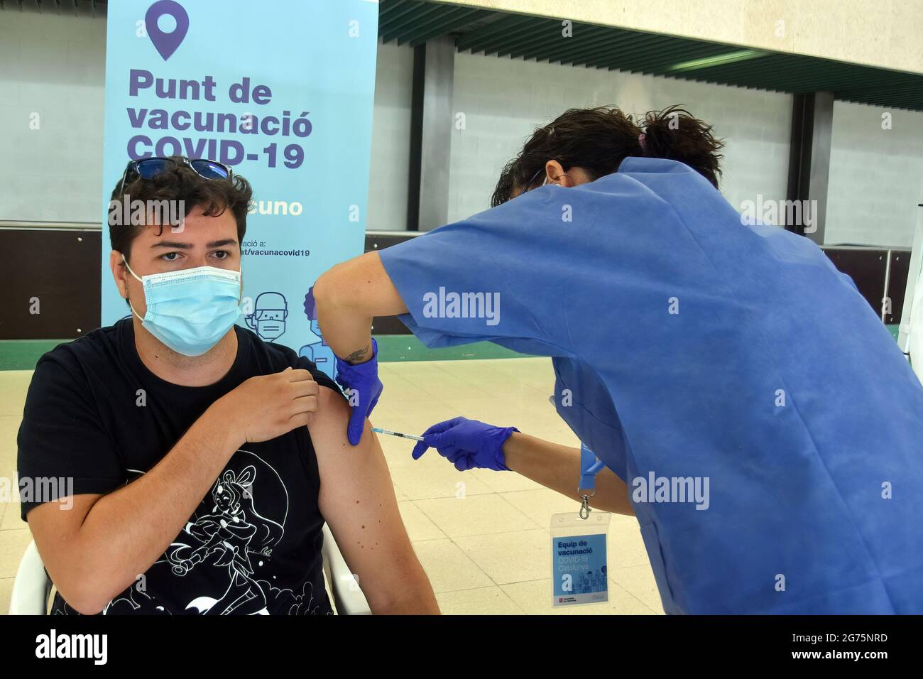 Calafell, Spain. 11th July, 2021. A health worker administers the first dose Comirnaty (PfizerBioNTech) COVID-19 mRNA Vaccine to a man at the Calafell Vaccination Center. The Department of Health of Catalonia through the Xarxa Santa Tecla de Tarragona in prevention against the contagion of SARS-CoV-2 Covid-19 has administered the first dose of the COMIRNATY vaccine (COVID-19 mRNA vaccine, Pfizer-BioNTech) to people between the ages of 16 and 34 at the vaccination center located at the Joan Ortoll Sports Pavilion in Calafell. Credit: SOPA Images Limited/Alamy Live News Stock Photo