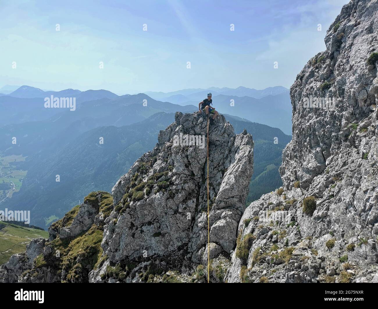 A young climber scaling a rock tower on a ridge in the Alps Stock Photo