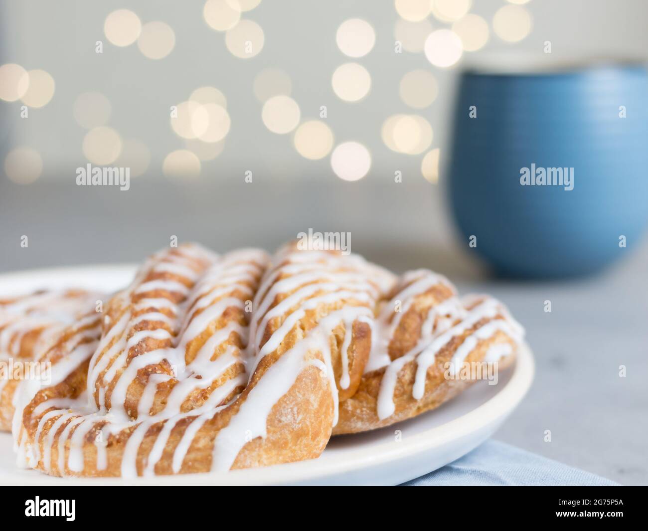 Cinnamon roll or cinnamon bun Dessert on plate with blue cup of coffee