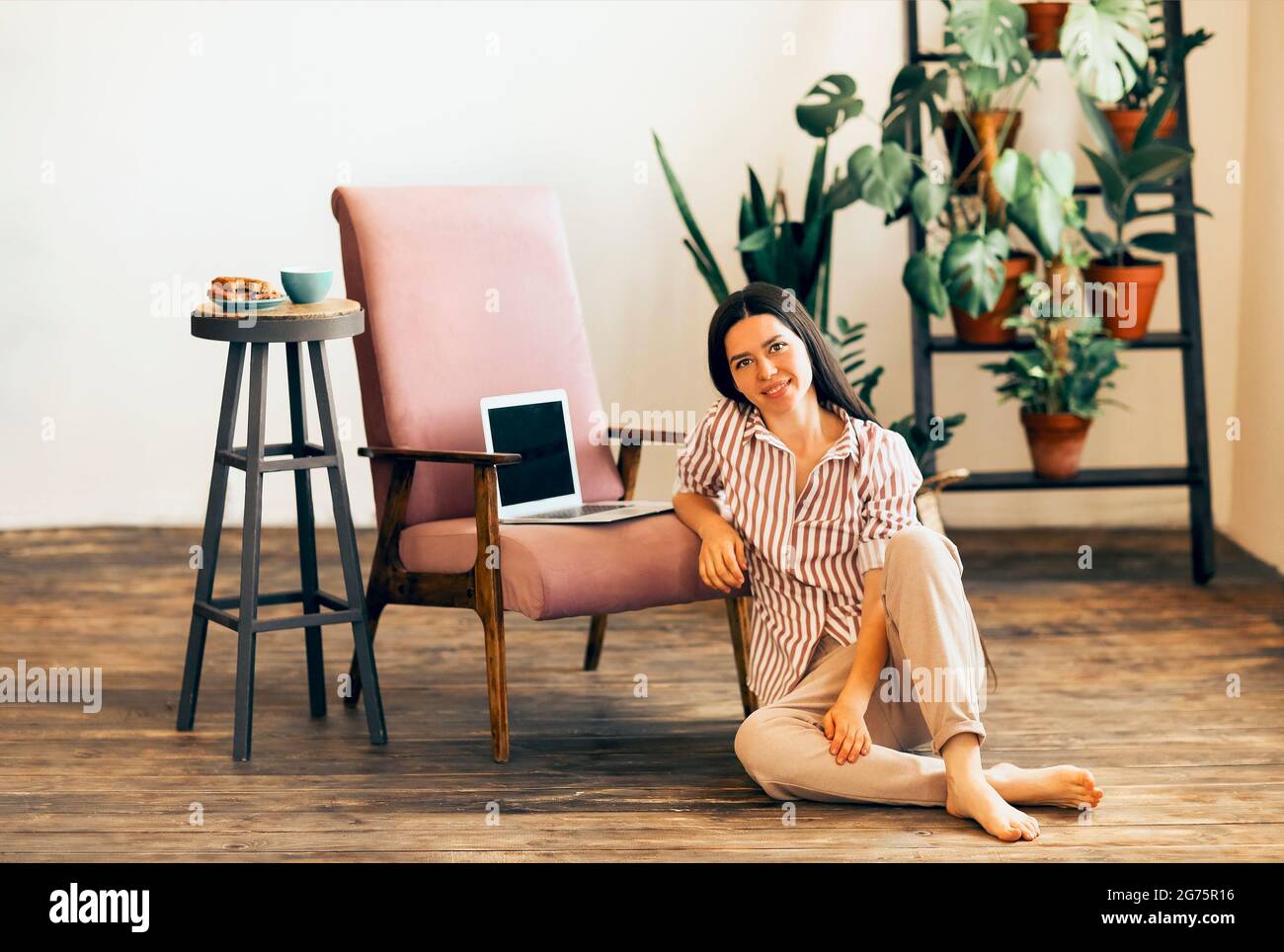 Calm female entrepreneur lying on wooden floor at home with laptop and