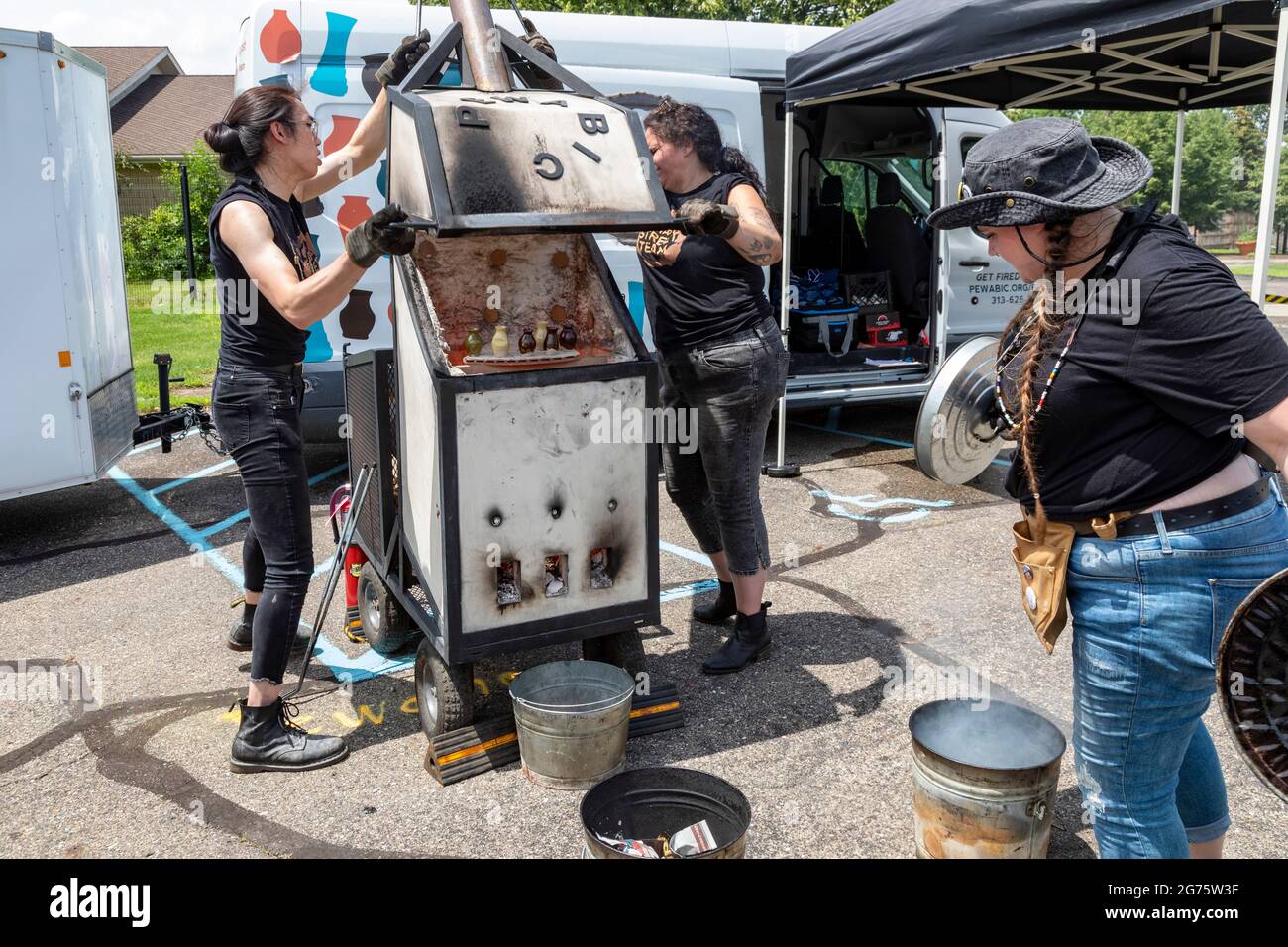 Detroit, Michigan - Members of the Pewabic Pottery Street Team demonstrate the Japanese technique of Raku Firing of pottery at a community arts and mu Stock Photo