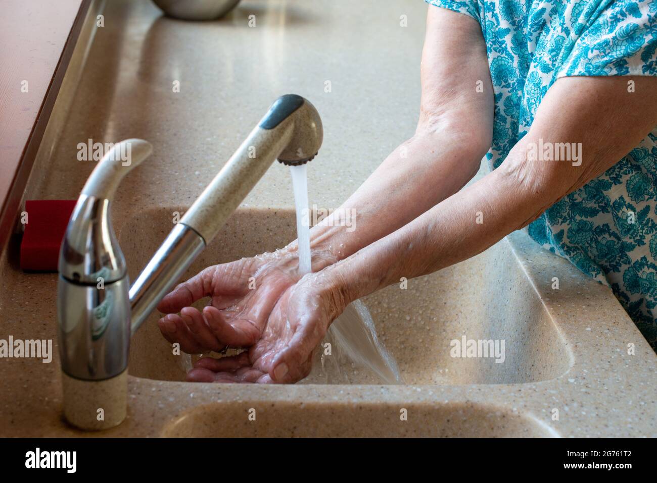 Senior woman's hands under cold running water. Close up. How to stay