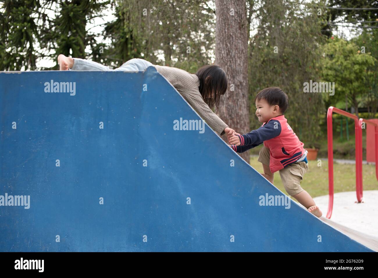 The older Malaysian child helping younger child up the ramp while ...