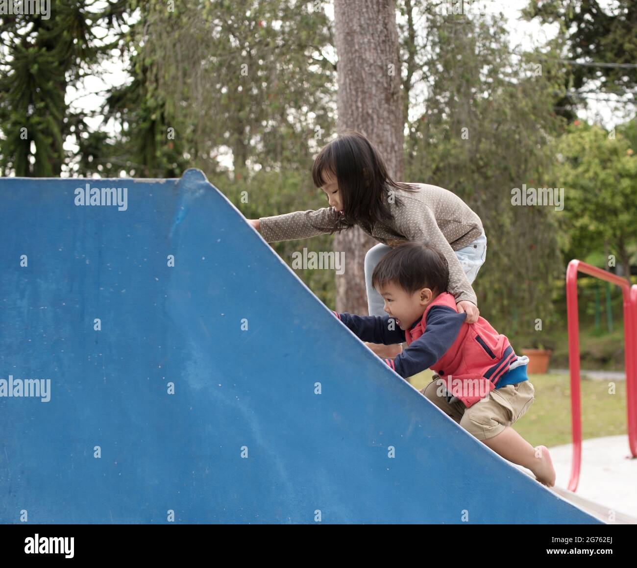 The older Malaysian child helping younger child up the ramp while ...