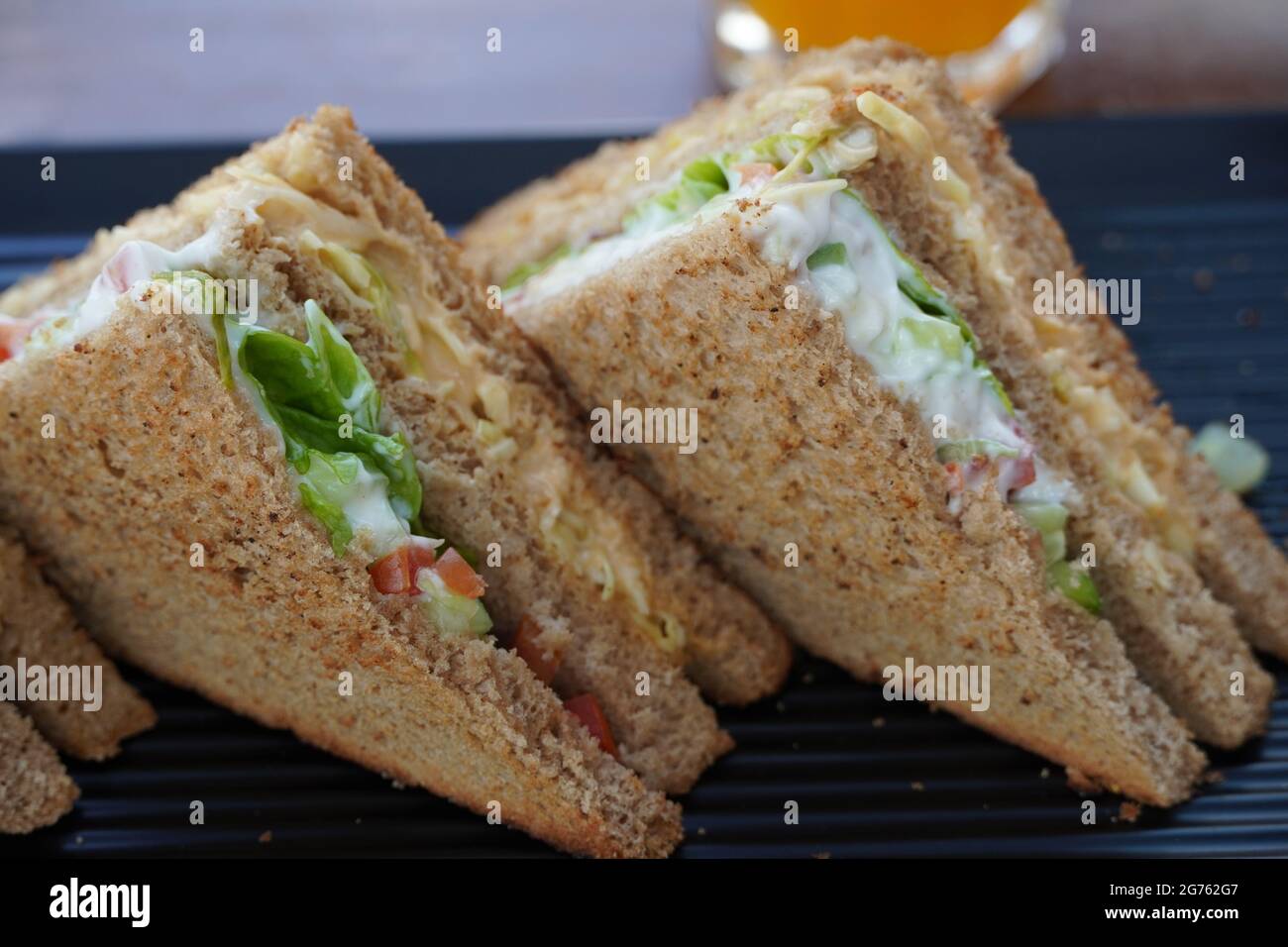 Two club sandwiches placed on a black plate at a restaurant. Closeup