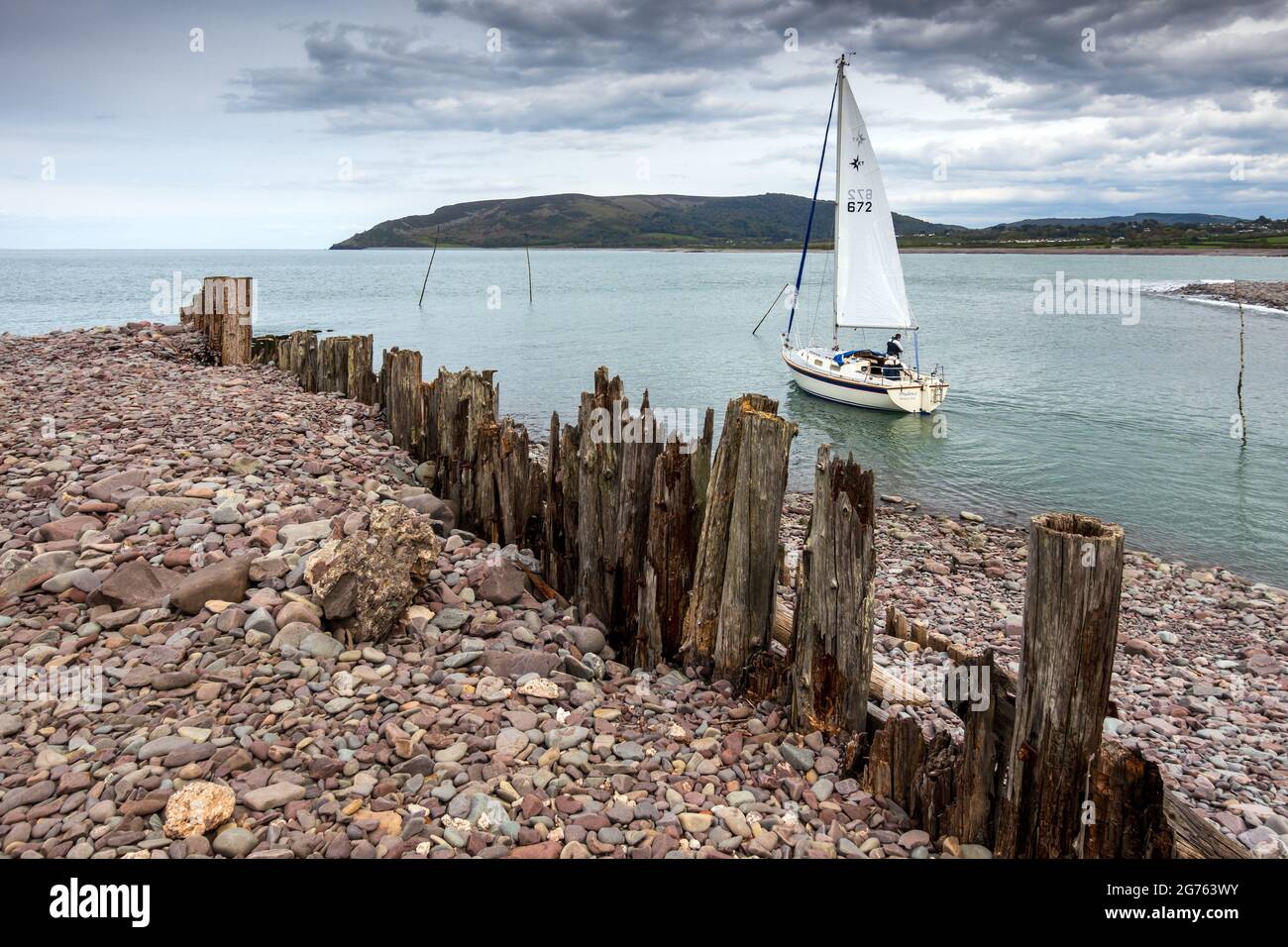 A yacht leaving the harbour at Porlock Weir on the Bristol Channel in Somerset. Stock Photo