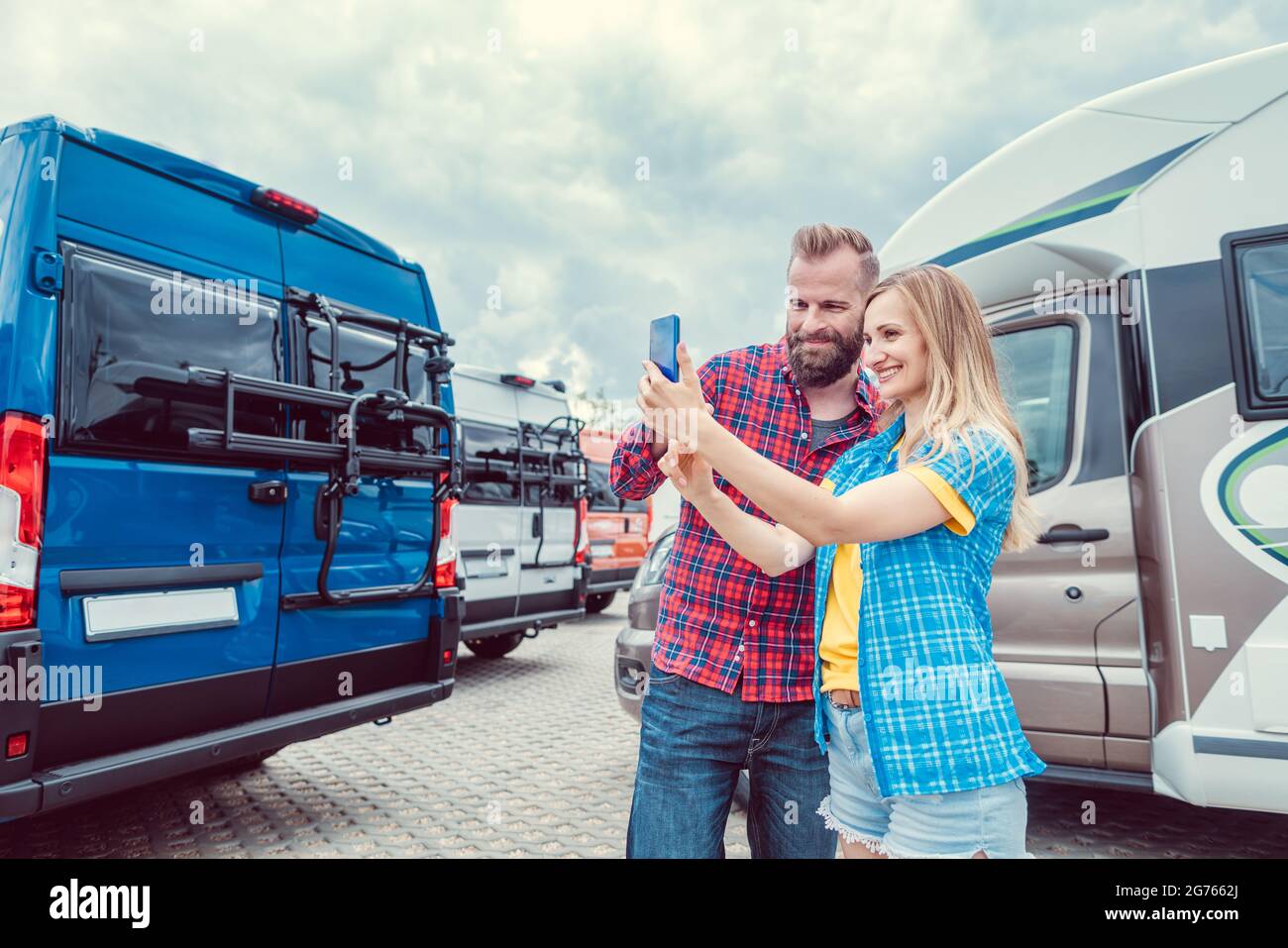 Woman and man taking selfie in front of RV or camper in anticipation Stock Photo