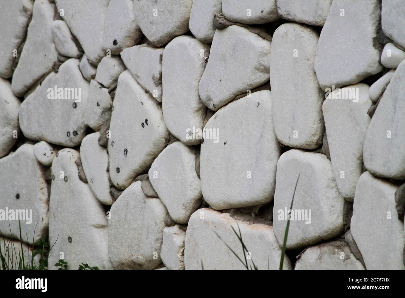Wall cladding made using white, rounded white stones and grass. Wall cladding made using rounded stones. Stock Photo