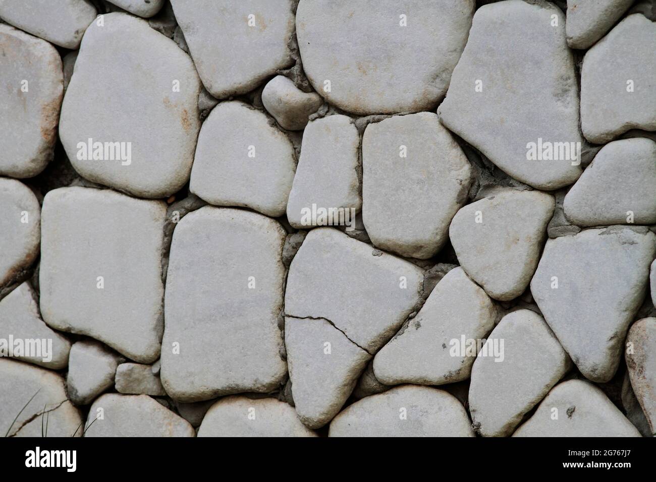 Wall cladding made using white, rounded white stones and grass. Wall cladding made using rounded stones. Stock Photo