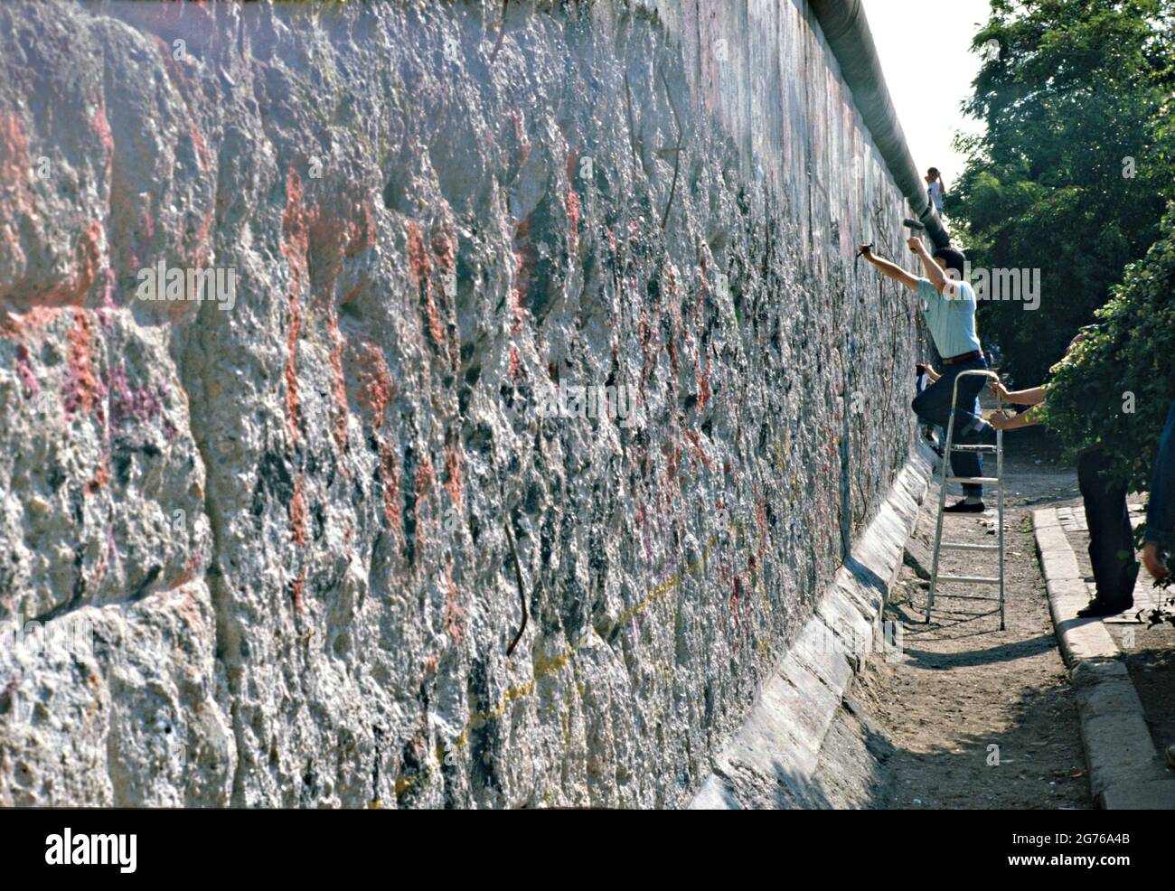 Berlin, Germany. 20 April 1990. Berlin Wall souvenir hunters known as Wallpeckers, chip away at a section of the Berlin Wall April 20, 1990 in West Berlin, West Germany. The wall separating East and West Germany came down November 9, 1989. Stock Photo