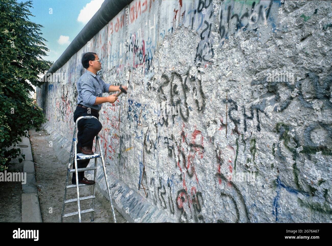Berlin, Germany. 20 April 1990. Berlin Wall souvenir hunters known as Wallpeckers, chip away at a section of the Berlin Wall April 20, 1990 in West Berlin, West Germany. The wall separating East and West Germany came down November 9, 1989. Stock Photo