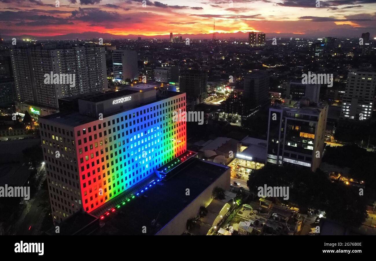 A drone image shows the ABS-CBN ELJ building projecting the company's signature colors on the eve of the first year anniversary of the rejection of a new franchise for the broadcasting network in Quezon City, Metro Manila. The Philippine Congress on July 10th 2021 voted to reject a new franchise for the multimedia network ABS-CBN, after the expiration of its 25-year operating franchise. Philippines. Stock Photo
