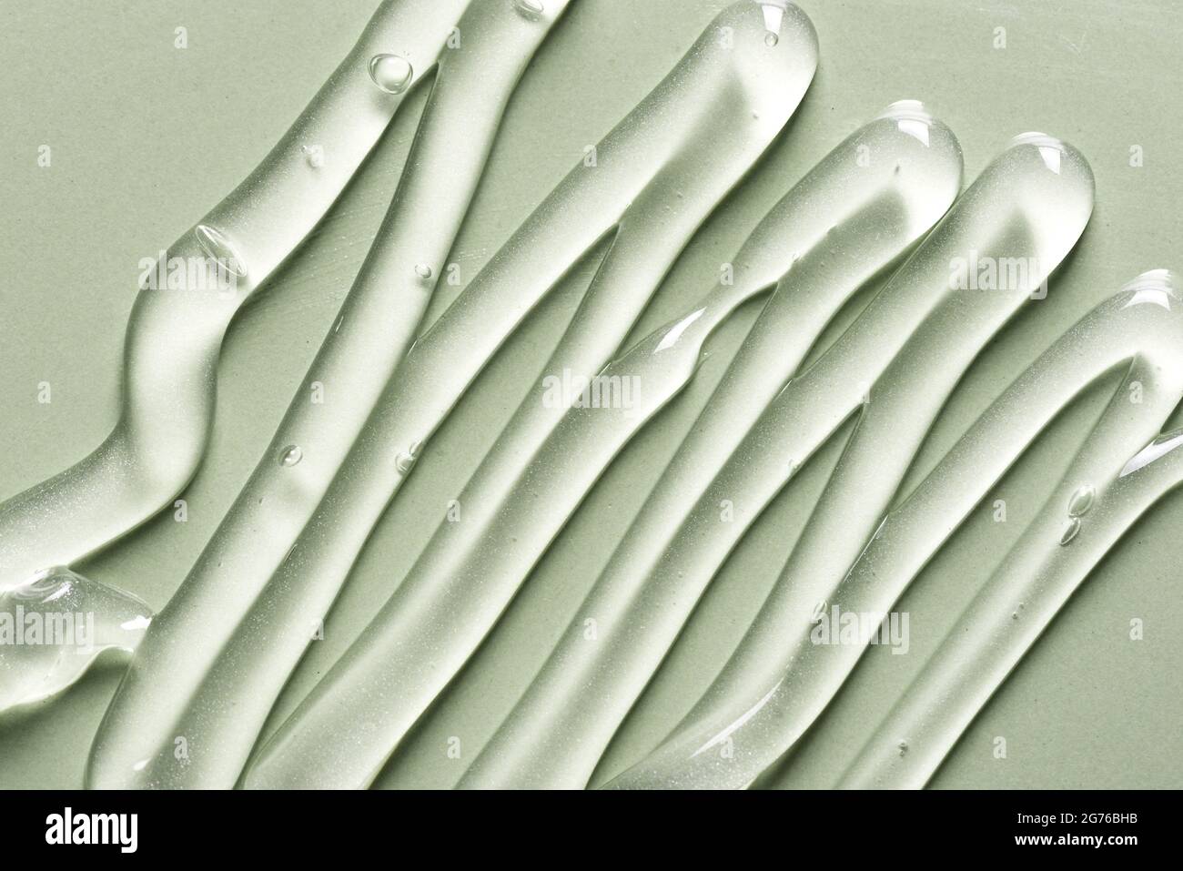 Gel texture on green background close up. Strokes of transparent gel