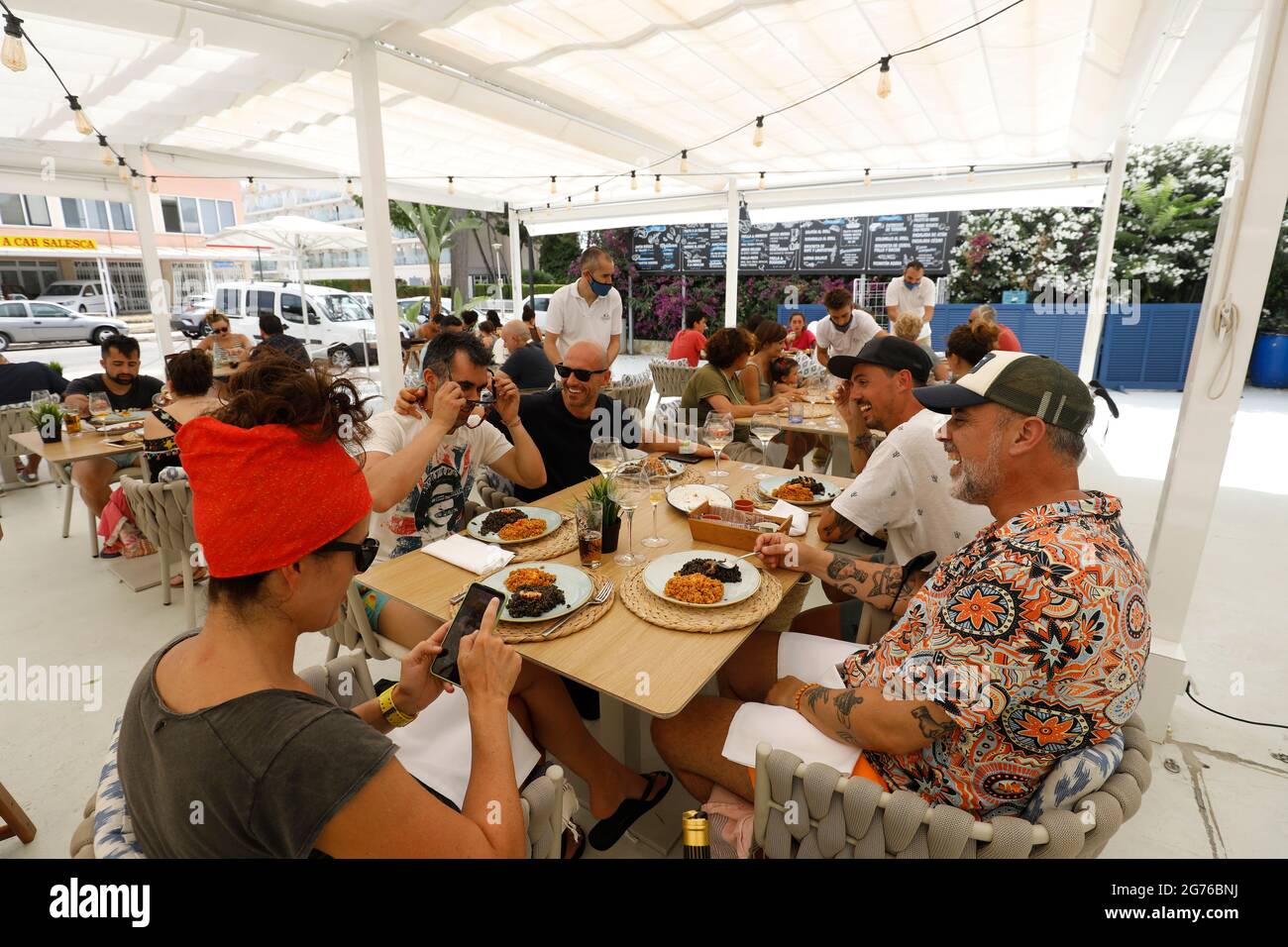 Muro, Spain. 11th July, 2021. A group of tourists eat in the restaurant Can Pescador on the beach Playa de Muro in the north of Mallorca. The federal government has declared the whole of Spain with Mallorca and the Canary Islands in view of rapidly increasing Corona numbers as a risk area. The practical effects for Mallorca holidaymakers are limited for the time being. Credit: Clara Margais/dpa/Alamy Live News Stock Photo