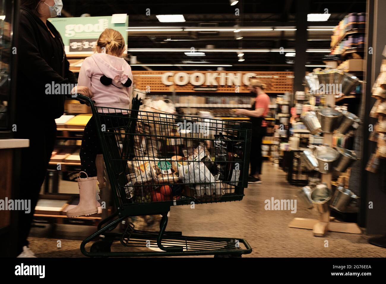 Person pushing a shopping cart with a child in it at the Whole Foods