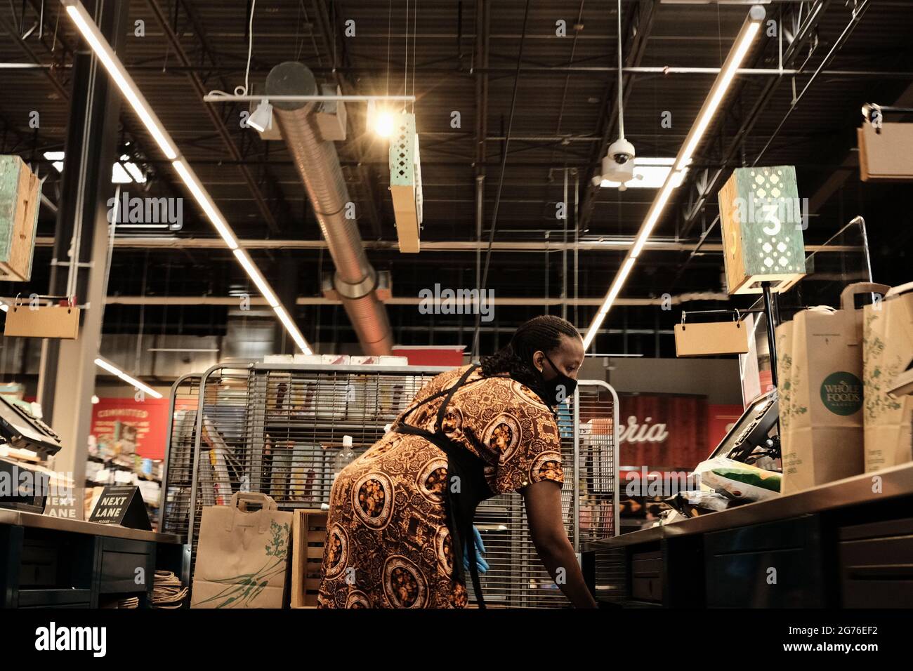 Cashier behind the till packs up a customer's shopping bags at the Whole Foods Market, Lansdowne, Ottawa, Ontario, Canada. Stock Photo