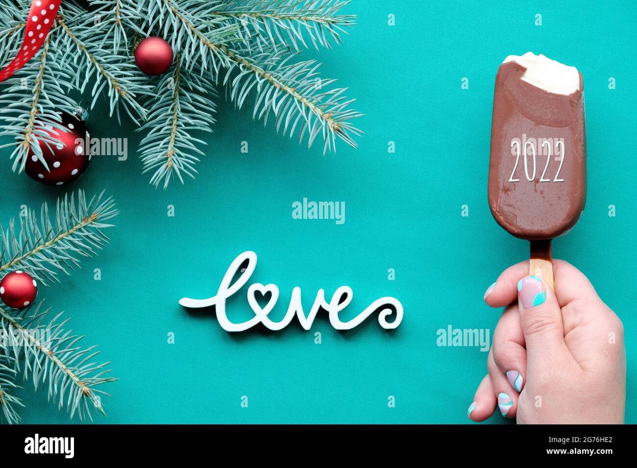 Happy New Year 2022. Hand With Ice Cream. Winter Ackground On Turquoise, Green Textile With Wooden Text Love. Top View On Fir Twigs Decorated With Red Stock Photo - Alamy