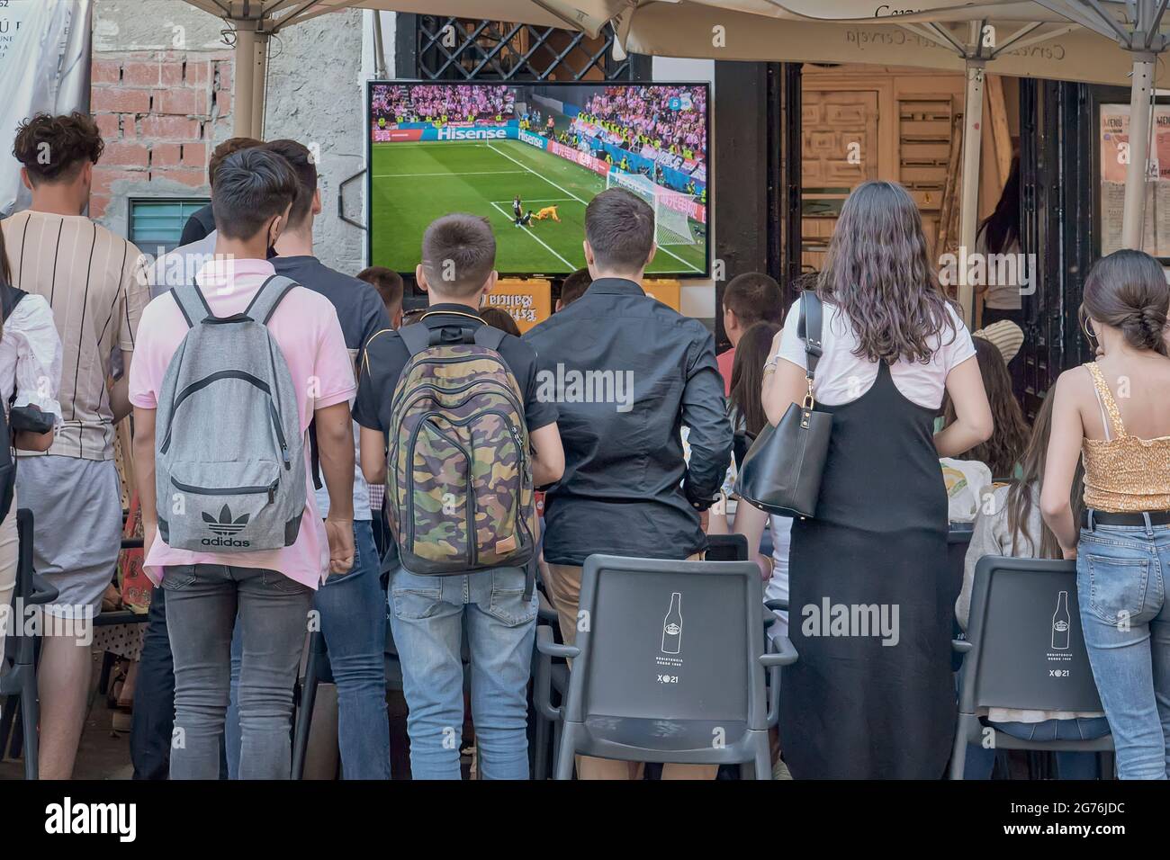 group of young boys and girls watching a soccer game on television on the terrace of a bar in the main square of the city of Cuenca, Spain, Europe Stock Photo