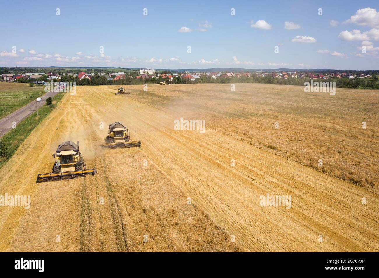 Aerial view of combine harvesters harvesting large yellow ripe wheat ...