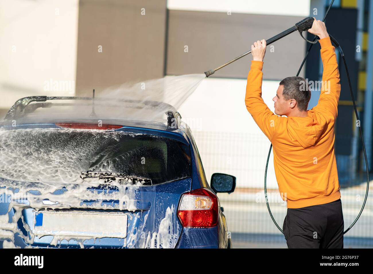 Young driver man washing his car with contactless high pressure water
