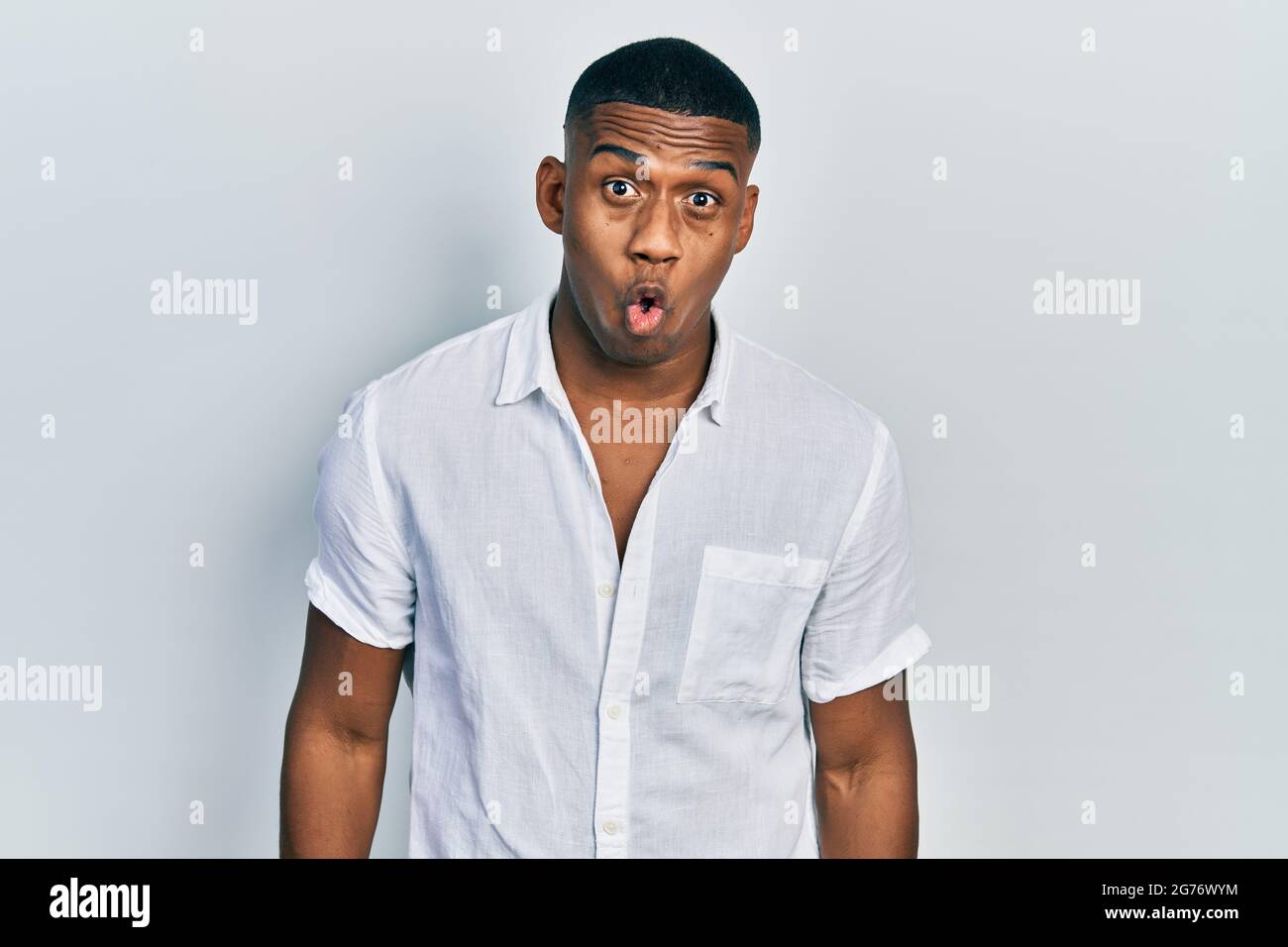 Young black man wearing casual white shirt afraid and shocked with ...