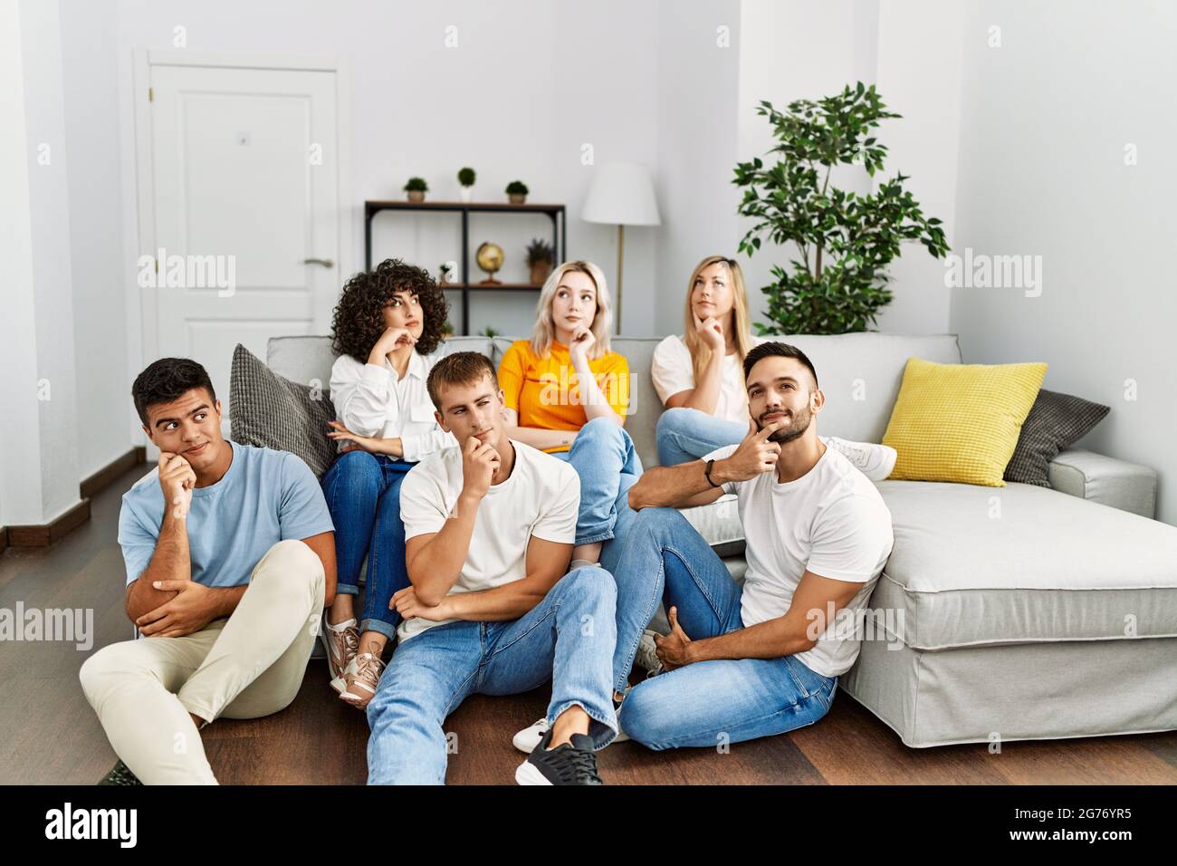 Group of people sitting on the sofa and floor at home serious face thinking  about question with hand on chin, thoughtful about confusing idea Stock  Photo - Alamy