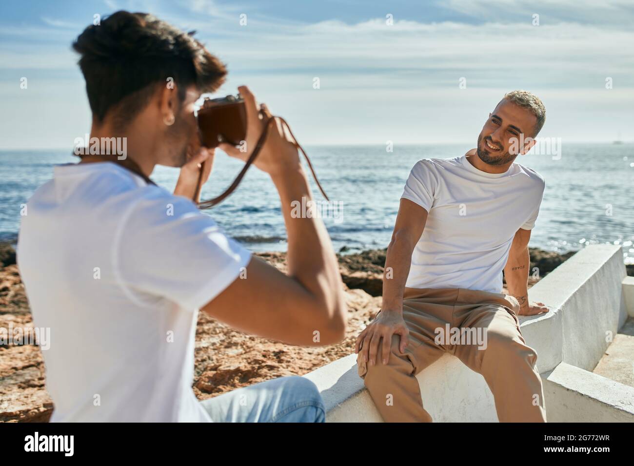 Man taking photos of his boyfriend in front of the sea. Stock Photo