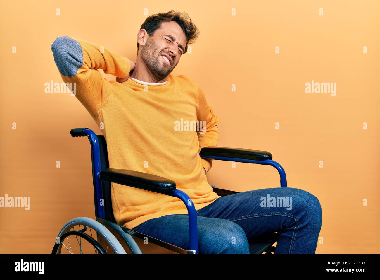 Handsome man with beard sitting on wheelchair suffering of neck ache