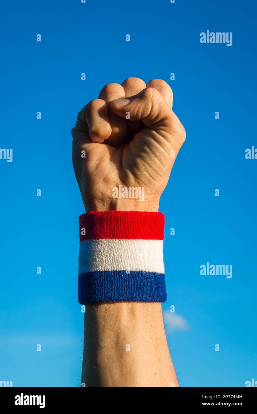 Close-up of hand of athlete wearing red white and blue colors wristband punching the air in celebration Stock Photo
