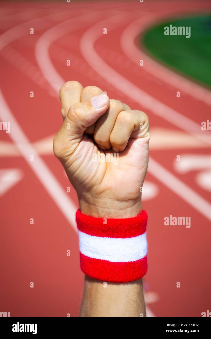 Japnese athlete  with red and white wristband punches the air in front of a sports track background Stock Photo