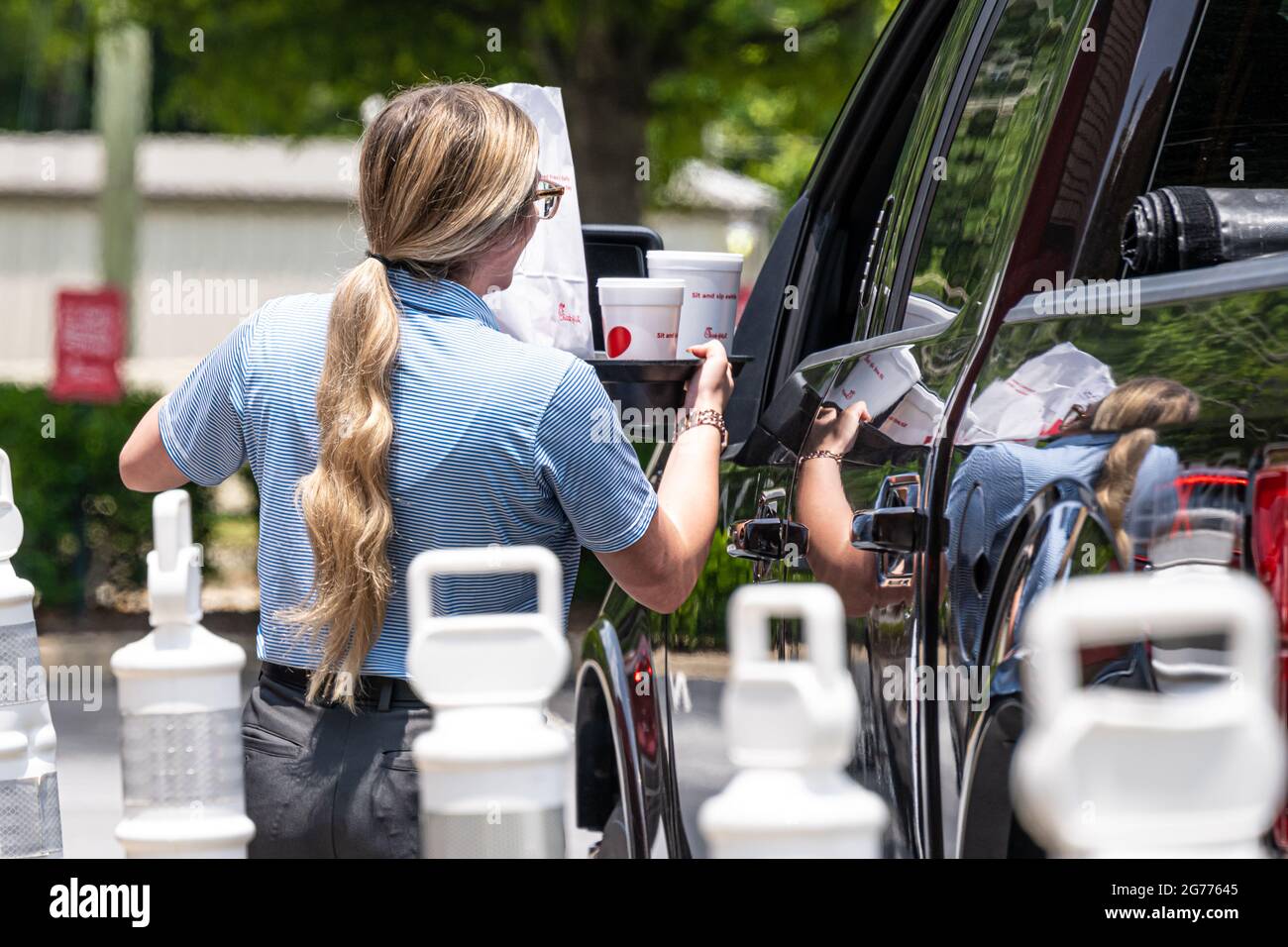 Chick-fil-A server delivering food order to a customer in one of the fast food restaurant's drive-thru lanes. (USA) Stock Photo