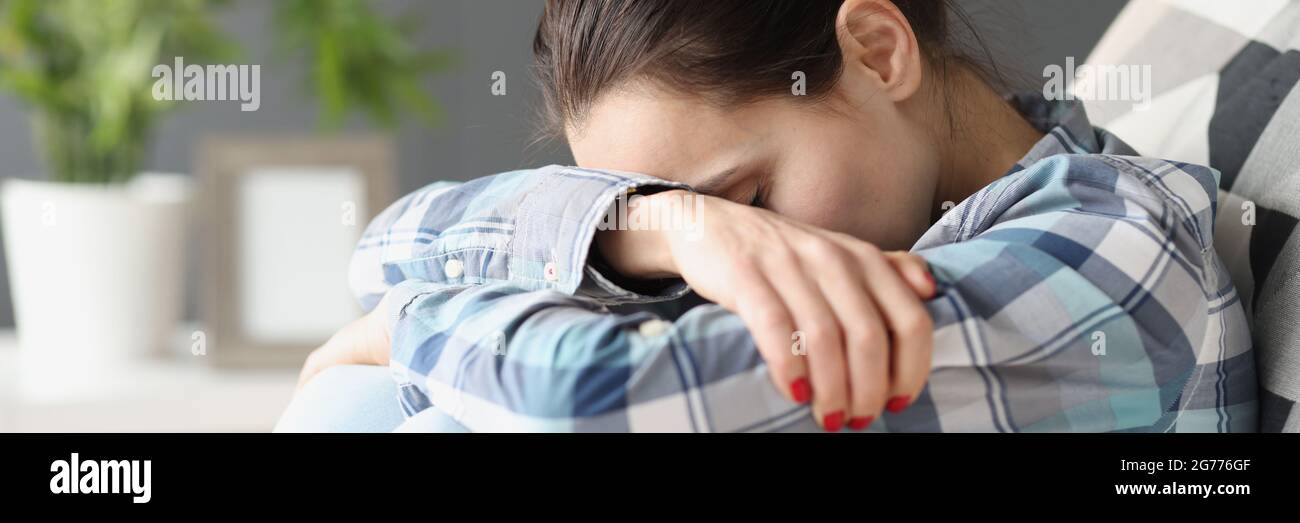 Sad woman sitting with her head bowed on sofa Stock Photo
