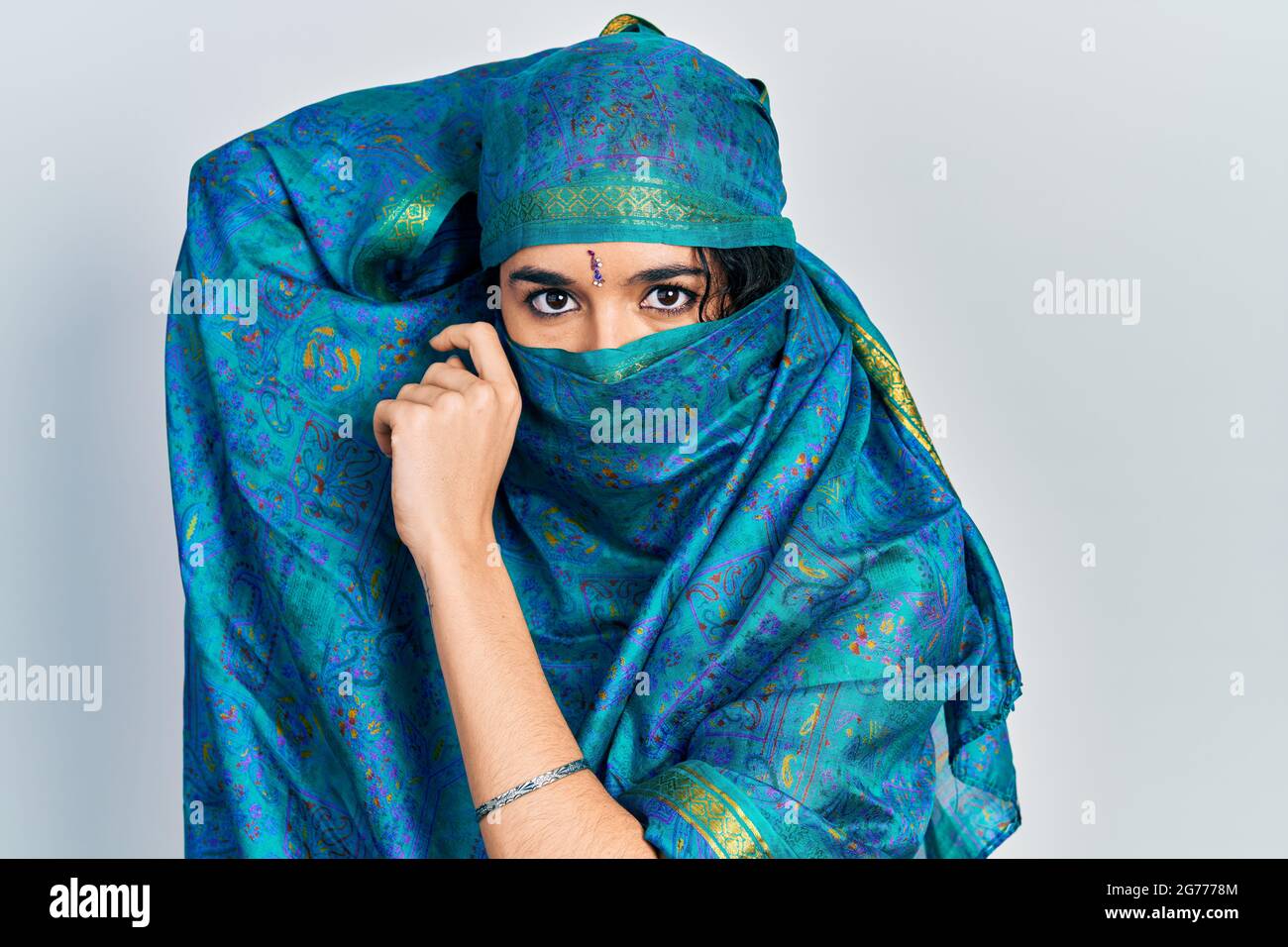 Young indian woman wearing sari covering head and face, doing elegant