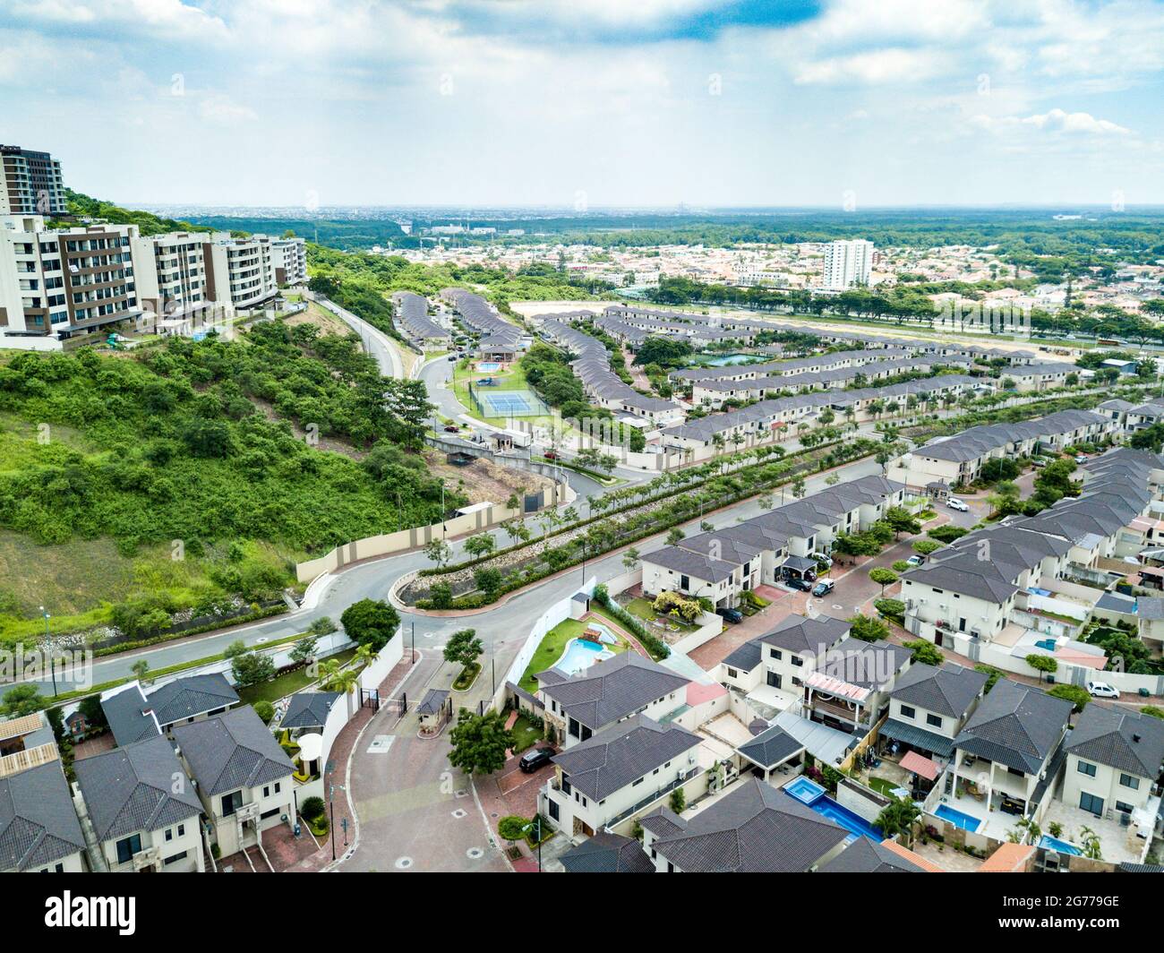 An aerial view of houses of a gated community un Guayaquil, Ecuador. Sunny day. Rooftops, playgrounds, trees, homes build next to each other. Stock Photo