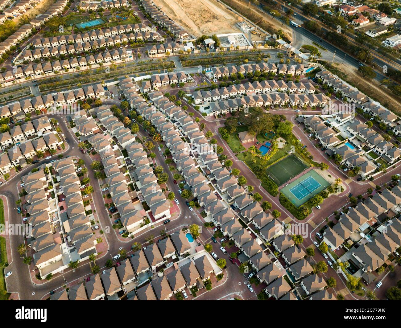 An aerial view of houses of a gated community un Guayaquil, Ecuador. Sunny day. Rooftops, playgrounds, trees, homes build next to each other. Stock Photo