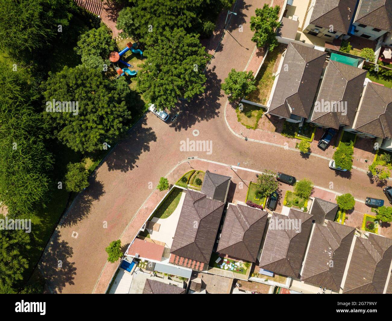 An aerial view of houses of a gated community un Guayaquil, Ecuador. Sunny day. Rooftops, playgrounds, trees, homes build next to each other. Stock Photo