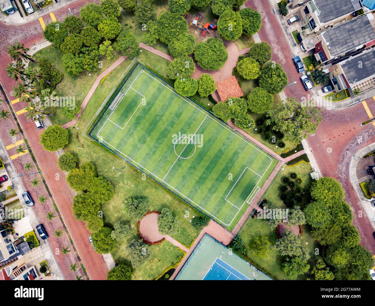 Straight down drone shot of empty mini soccer field and tenis court surrounded by park and trees in a gated community outside Guayaquil City, Ecuador. Stock Photo
