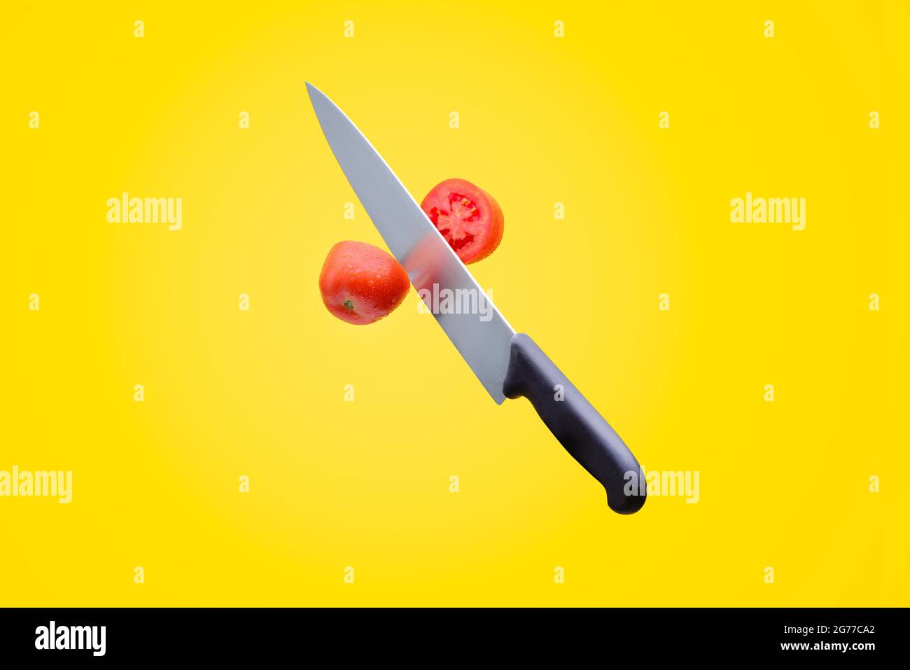 knife cut red tomato, Mexican tomato, yellow background, fresh fruit, cut in the air, chef's knife Stock Photo