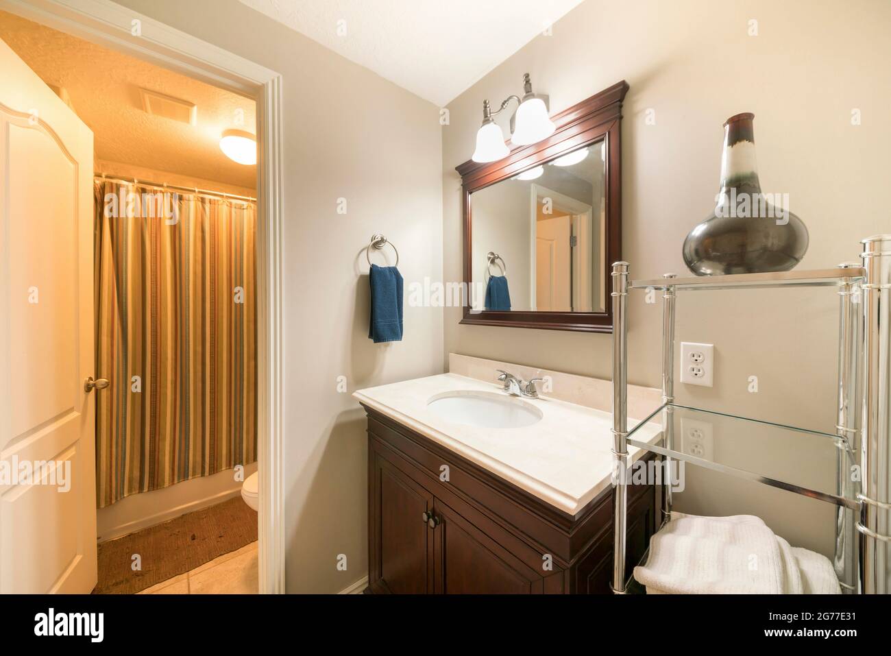 Bathroom interior with wooden vanity unit beside a steel and glass ...