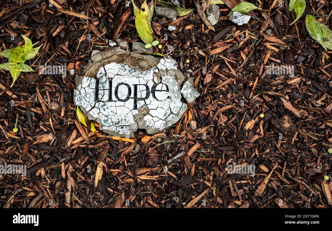 Shattered or lost hope concept as suggested by image of cracked stone printed with the word Hope. Could also suggest hope can prevail over adversity. Stock Photo
