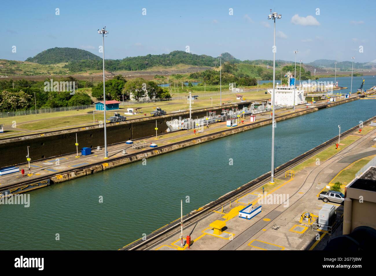 A large cargo just passed through Panama Canal in a sunny day. The main offices and one of the locks can be seen. Stock Photo