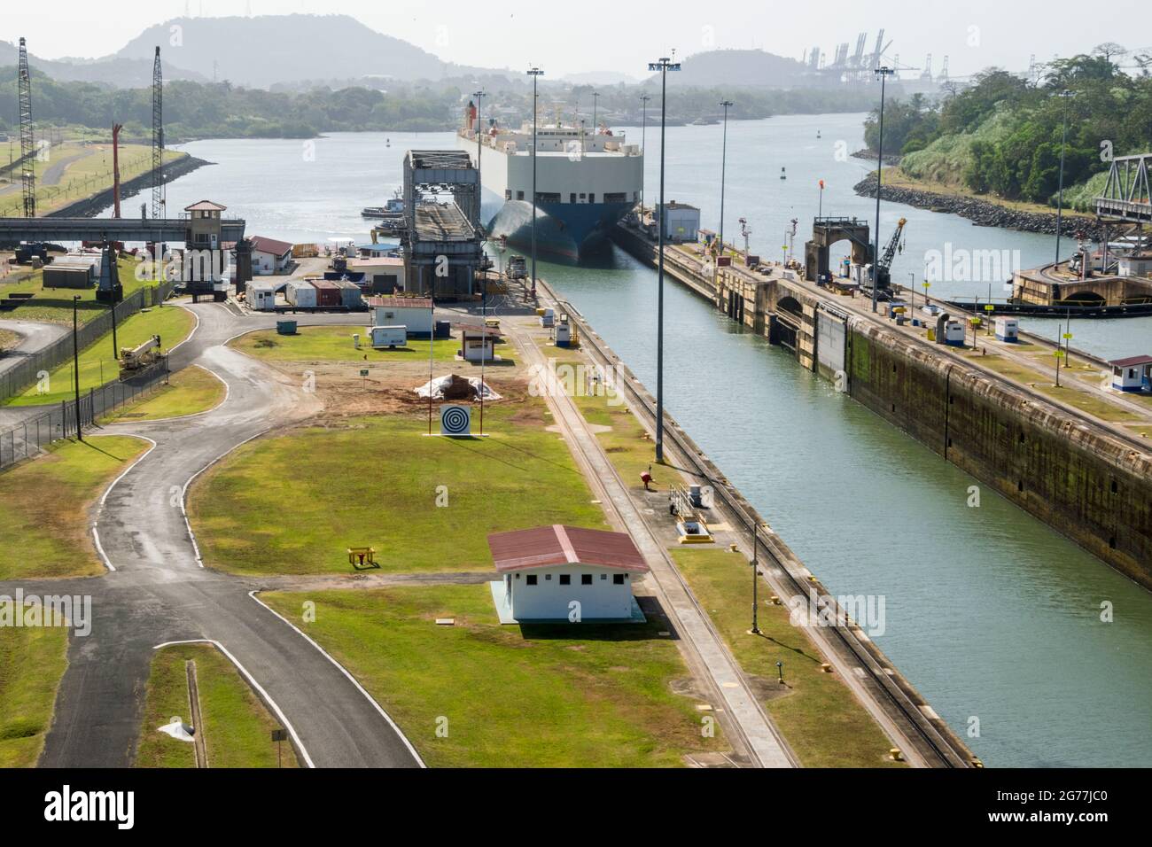 A large cargo just passed through Panama Canal in a sunny day. The main offices and one of the locks can be seen. Stock Photo