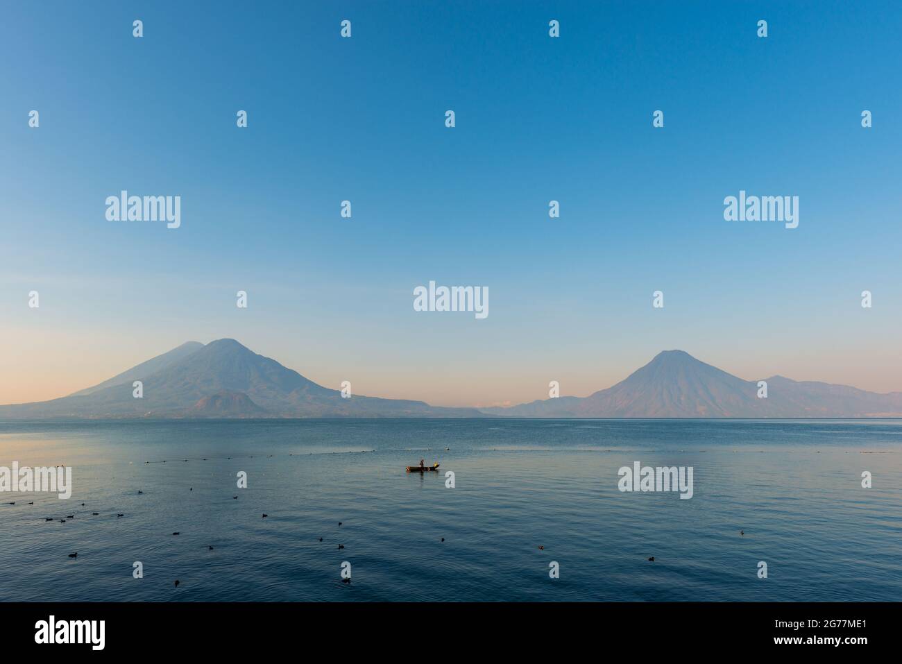 Atitlan Lake with Toliman, San Pedro and Atitlan volcano at sunrise and fisherman, Panajachel, Guatemala. Stock Photo