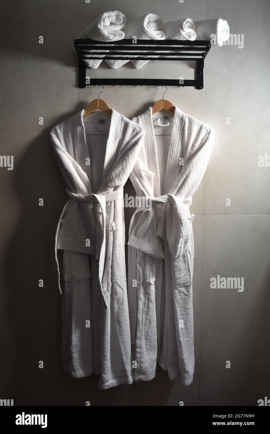 Spa Robe Rack Vertical shot of two spa robes hanging on a black wall rack with rolled ...