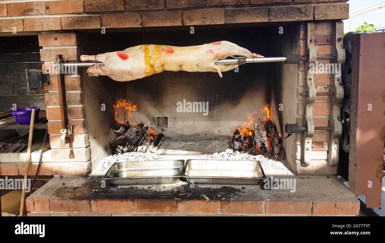 Spit Roasted Lambs, traditional way of roasting lambs on a rotisserie spit in Bulgaria. Cooking and roasting whole lamb called cheverme at a restauran Stock Photo