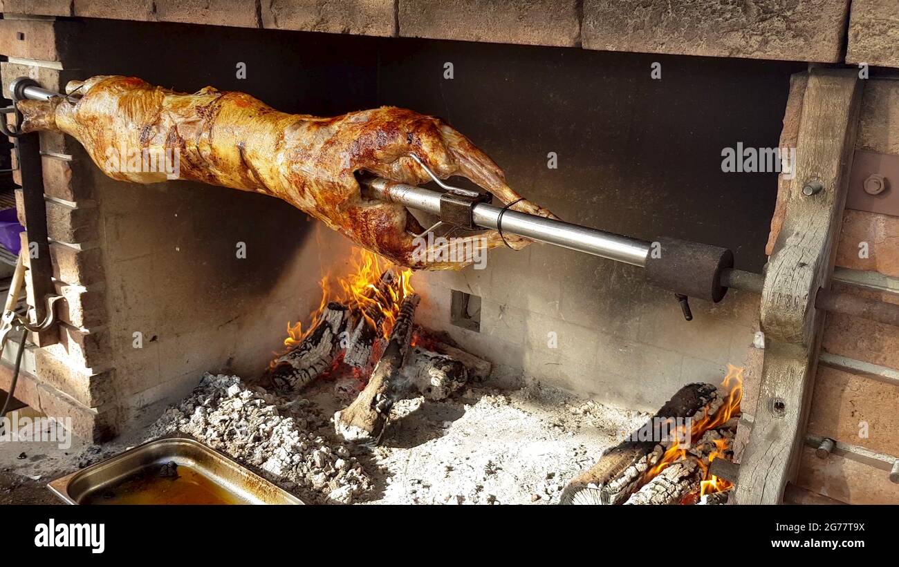 Spit Roasted Lambs, traditional way of roasting lambs on a rotisserie spit in Bulgaria. Cooking and roasting whole lamb called cheverme at a restauran Stock Photo