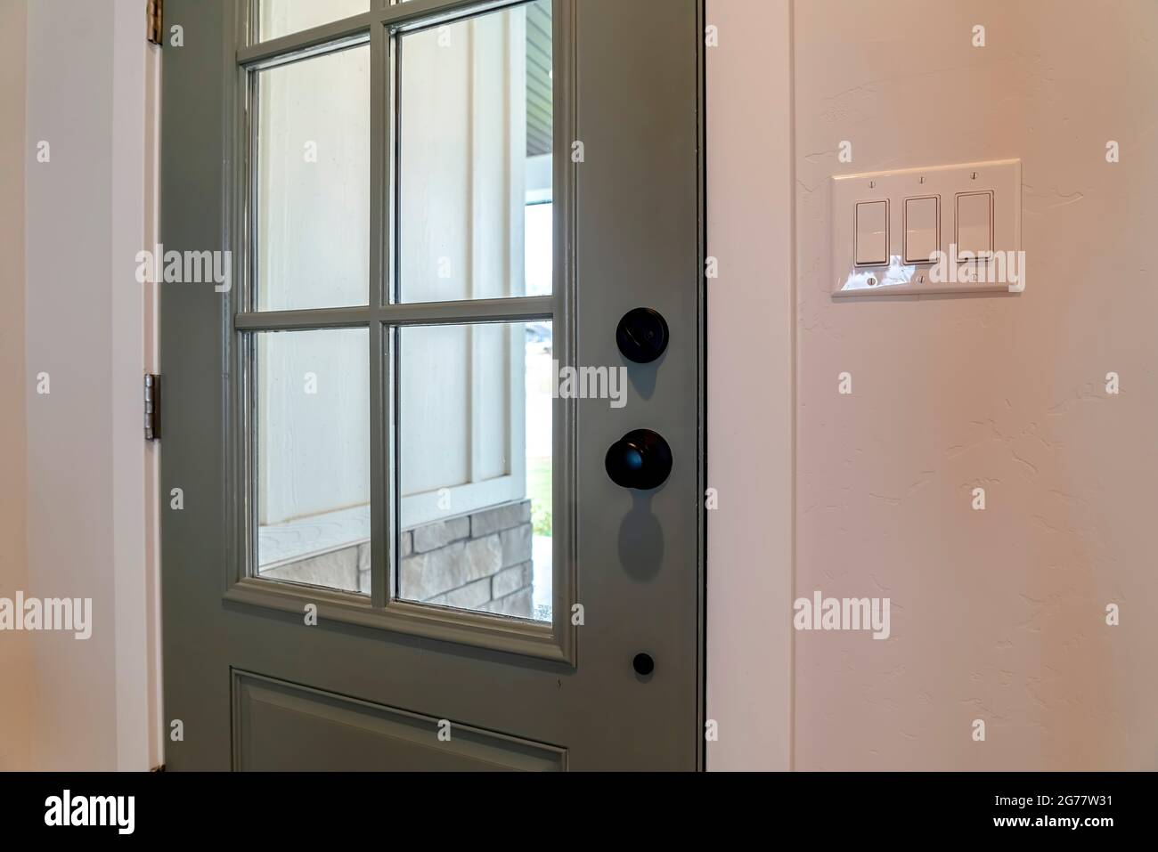 Close up of wooden front door of home with glass panel and black doorknob Stock Photo