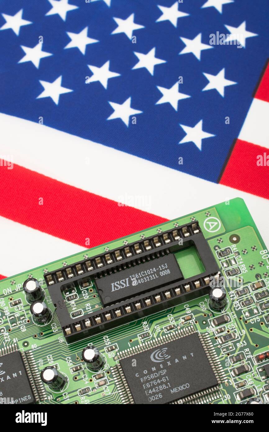 US Stars and Stripes flag with green PCB circuit board with empty EPROM socket. For 2021 integrated computer chip shortages, semiconductor shortages. Stock Photo