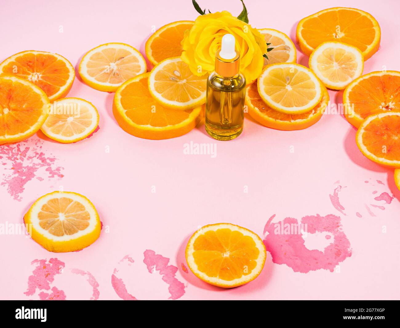 Vitamin C serum bottle with dropper on pink background with orange