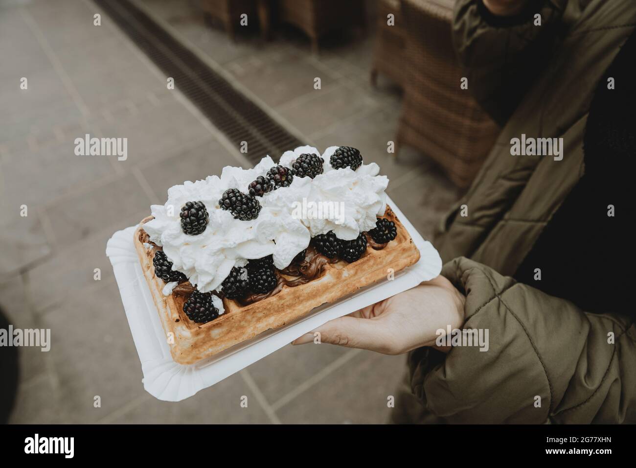Detail of the Traditional Polish specialty gofry with whipped cream and blackberries on woman hand Stock Photo